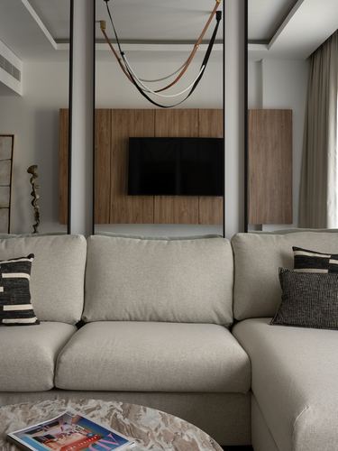 Beige sectional sofa facing wood-paneled TV wall with hanging straps and black column frames