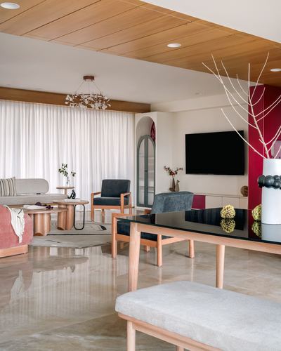 Open-plan living and dining space with marble floor, wood ceiling, red accent wall and tv console