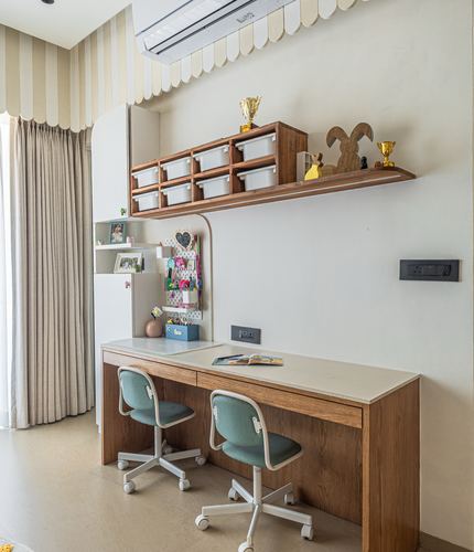 Children's study nook with two teal chairs at a wooden desk under a floating storage shelf