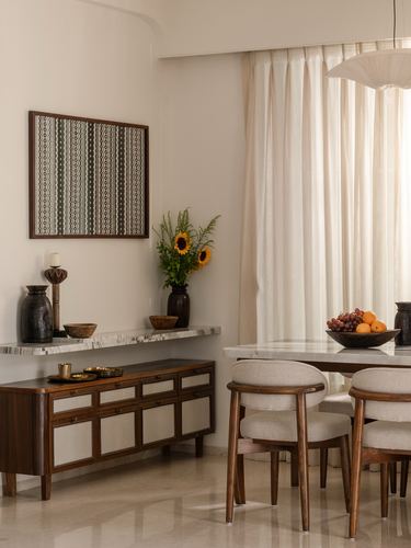 Dining area with marble-topped sideboard, framed textile art, sunflowers, and wooden dining chairs