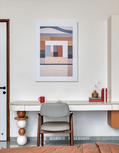 Study nook with floating white desk, cane-backed wooden chair, and abstract geometric artwork above