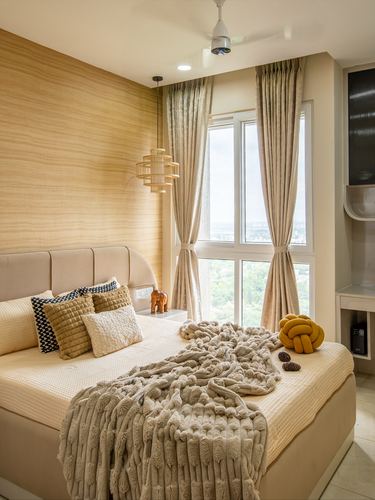 Bedroom with wood-panel wall, cane pendant light, beige bed with knit throw and city view window