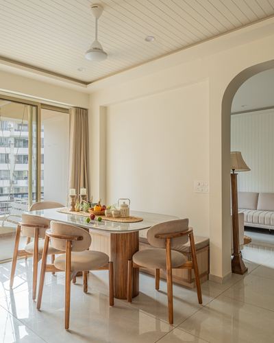 Dining table with fluted pedestal base and cane chairs beside arched doorway to living room