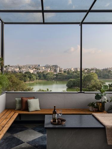 Rooftop terrace bench overlooking a lake and city skyline under a glass canopy