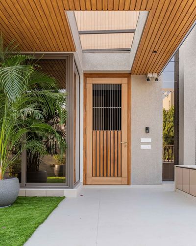 Entry facade with wood-slat door, textured stone wall, and skylight above porch