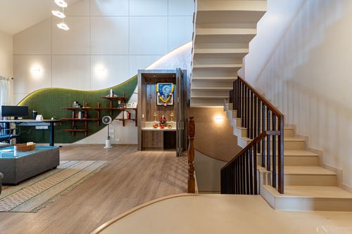 Foyer with curved staircase, green tiled wall with shelving, and glass-fronted pooja niche