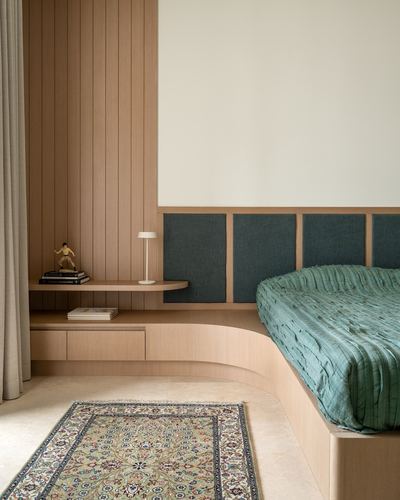 Curved wood-panelled bedroom with green upholstered headboard and floating nightstand over marble floor