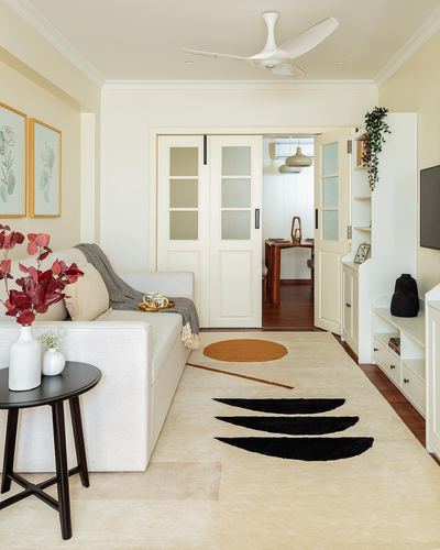 Cream living room with patterned rug, white sofa, and glazed doors opening to dining area