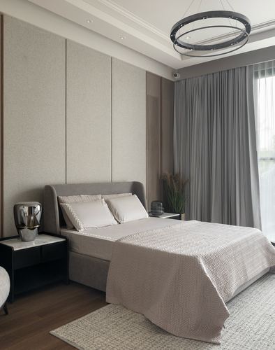 Neutral-toned bedroom with upholstered wall panels, grey curtains, and a circular ring chandelier