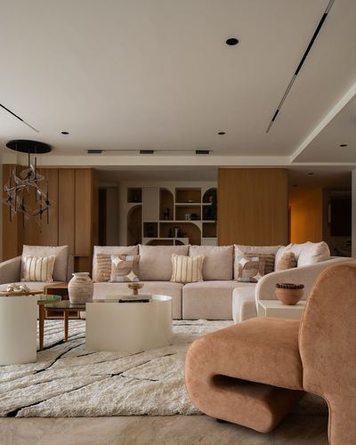 Warm-toned living room with curved beige sectional, terracotta sculptural chair, and arched wood shelving.