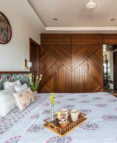 Bedroom with chevron wood wardrobe, floral headboard, and printed bedding with breakfast tray