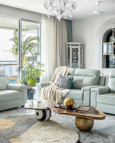Sage green leather sofas around live-edge wood coffee tables with brass bases in a bright living room
