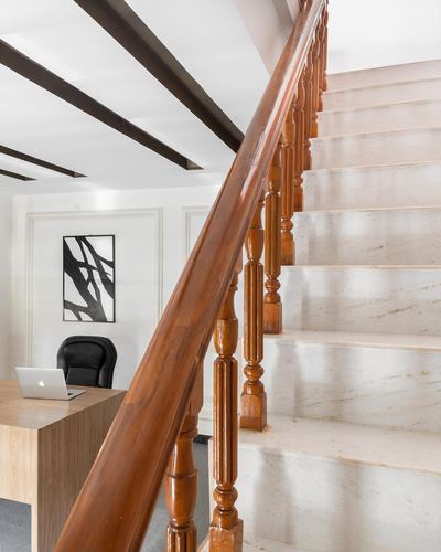 Staircase with turned wood balusters and stone treads beside a small home office with desk and chair