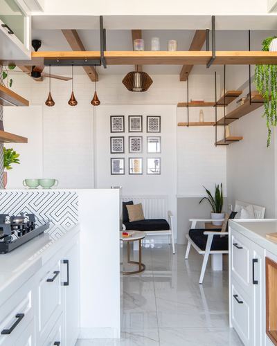White kitchen with patterned backsplash opening into a seating nook under exposed wood beams