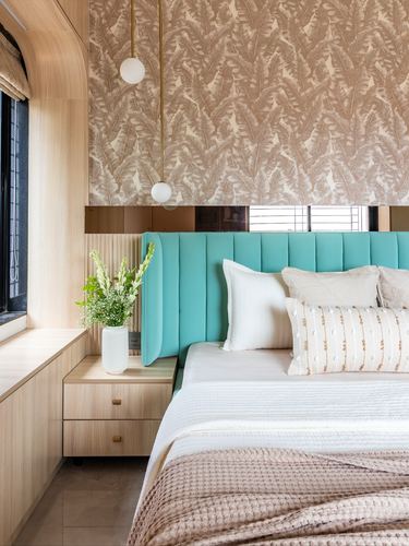 Bedroom with teal fluted headboard, botanical wallpaper, wooden nightstand and pendant lights
