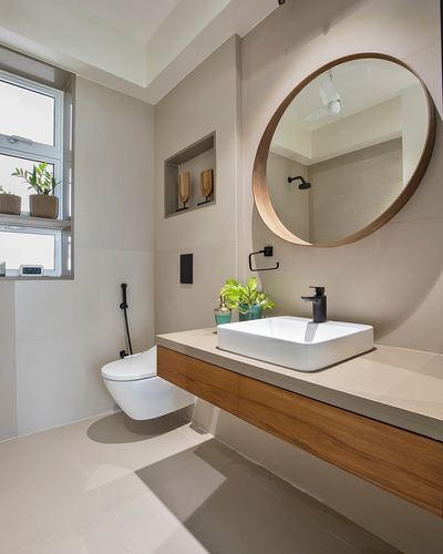 Beige bathroom with wooden vanity, vessel sink, round mirror, and wall-hung toilet by window