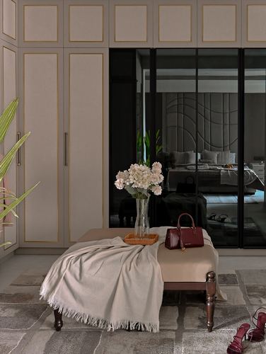 Cushioned bench with throw and flowers before a mirrored wardrobe reflecting the bedroom beyond.