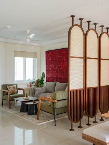 Living room with cane-panel wooden screen, olive armchairs, grey sofa and red textured wall art