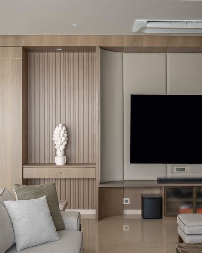 Living room with fluted wood niche, sculptural vase, and padded panel wall mounted tv