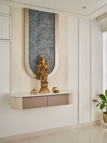 Arched blue-grey textured niche with brass Ganesha statue above a floating fluted console