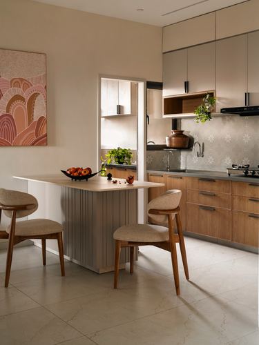Beige kitchen with wood cabinetry, fluted island, patterned backsplash and two wooden chairs