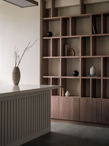 Fluted console with vase beside a large asymmetric wooden grid shelving unit holding decor