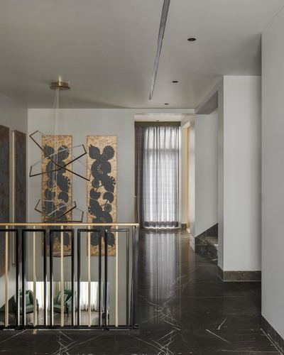 Landing hallway with dark marble floor, brass-black railing, sculptural pendant and floral panel art