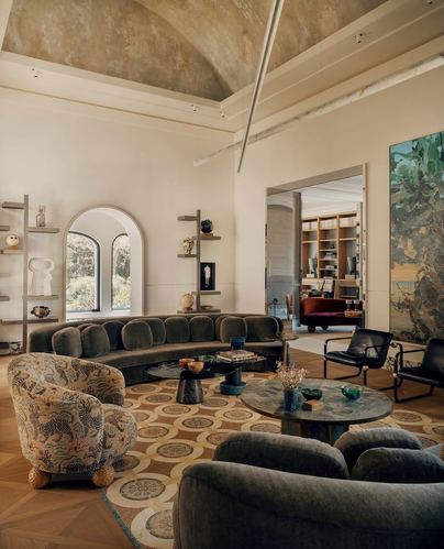 Living room with vaulted plaster ceiling, curved olive sofa, arched window, and patterned rug in Amman home