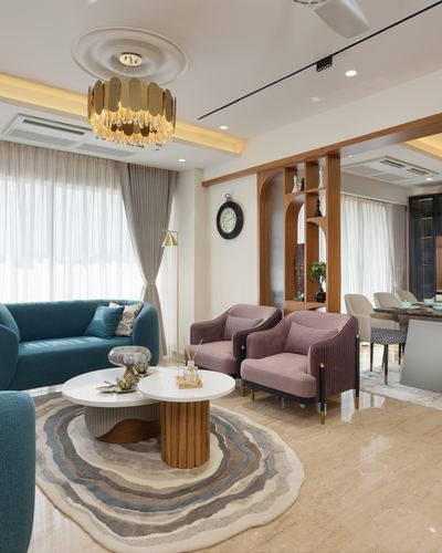 Living room with teal sofa, mauve armchairs, round marble coffee tables, and gold chandelier
