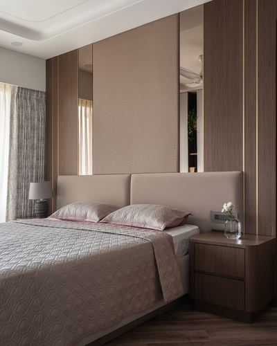 Bedroom with brown fluted veneer wall, leather headboard, mirrored panels, and pink quilted bedding