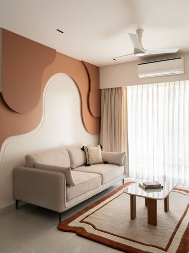 Beige sofa against a sculptural terracotta wall mural in a minimal living room