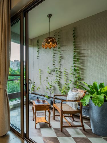 Balcony seating nook with cane bench, wooden table, and vines climbing a trellis wall