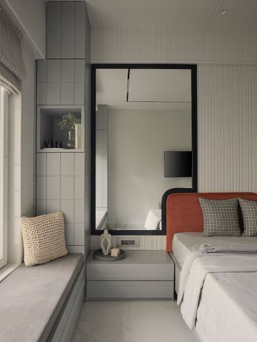 Bedroom corner with tiled niche, black-framed mirror, and orange corduroy headboard