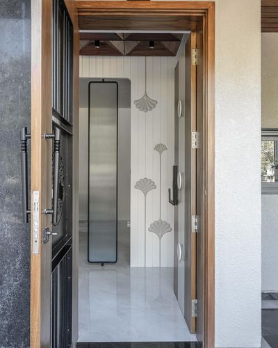 Open wooden door revealing a white fluted foyer with floral wall reliefs and mirror
