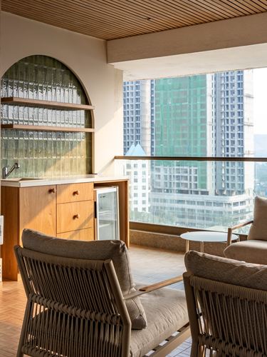 Balcony lounge with wooden ceiling, arched glass niche, rope chairs and city skyline view
