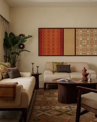 Living room with cream sofas, fluted wood coffee table, kilim rug, and framed textile art panels on wall