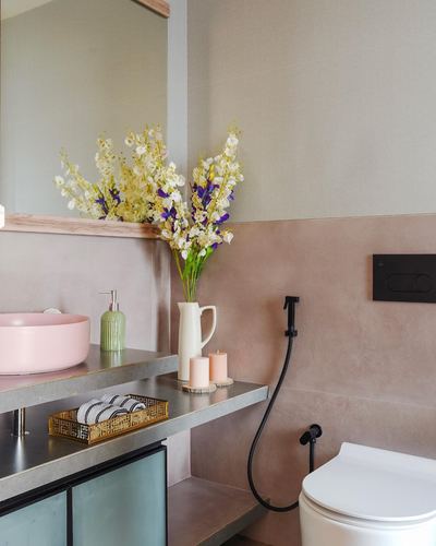 Bathroom with pink vessel sink, floral arrangement, and blush plastered wall behind toilet