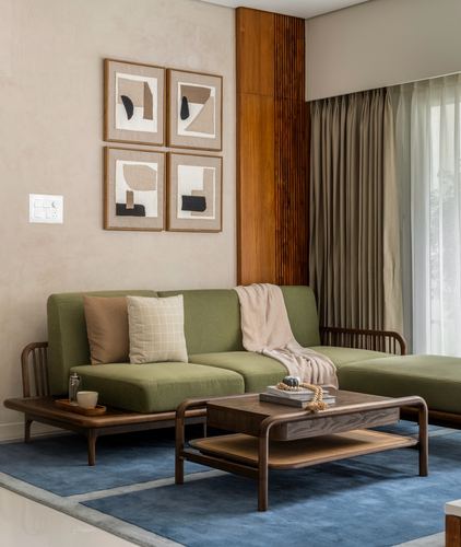 Olive green sofa with wood coffee table beneath framed abstract art on textured wall