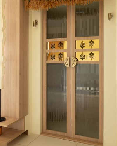 Wooden double door with fluted glass and brass floral inlays in a warm-toned foyer