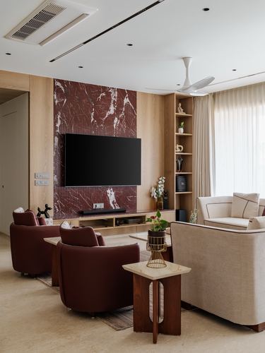 Living room with red marble tv wall, wood panelling, burgundy armchairs and cream sofa