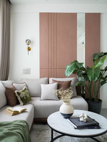 Beige sectional sofa against terracotta panelled wall with mirror strip and round marble coffee table
