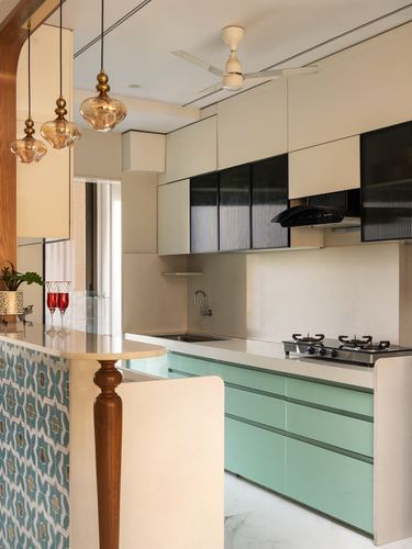 Mint green kitchen with amber pendant lights and patterned tile counter, Mumbai apartment