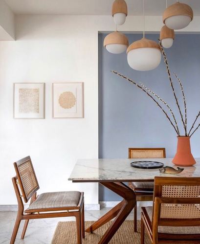 Dining table with marble top, cane chairs and orb pendant lights against a blue niche wall