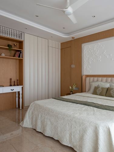 Bedroom with fluted white wardrobe, wood panelling, and textured floral wall relief above bed