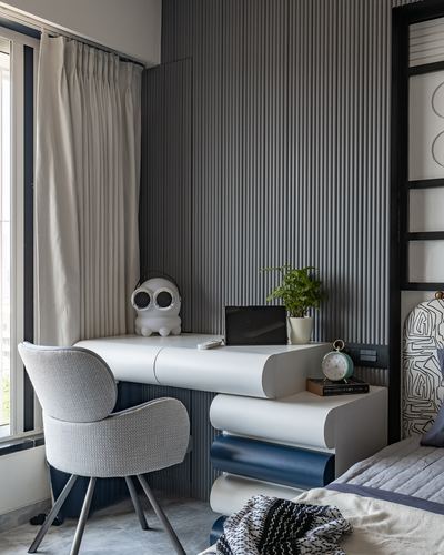 Study nook with fluted grey wall, curved white desk, and boucle chair by window