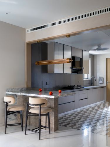 Modern kitchen island with marble top, brass pendant light, and mirrored dark cabinetry