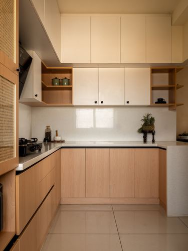 L-shaped kitchen with wood veneer lower cabinets, white uppers, cane panel, and terrazzo-look counter