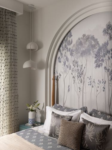 Bedroom with arched plaster niche, tree mural headboard, patterned pillows and paired pendant lights