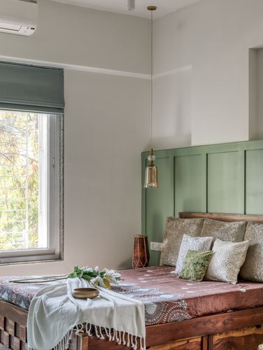 Bedroom with sage green paneled headboard wall, wooden bed, and pendant light beside a window