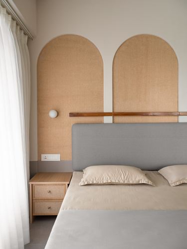Bedroom with two arched fabric wall panels behind a grey upholstered bed